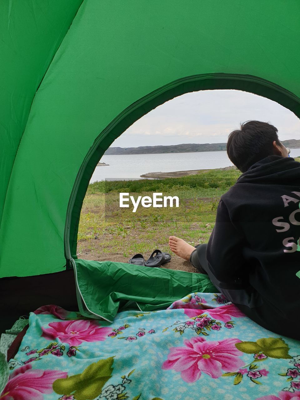 Rear view of teenage boy sitting in tent