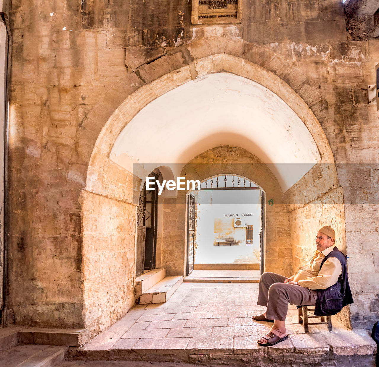 MAN SITTING OUTSIDE BUILDING