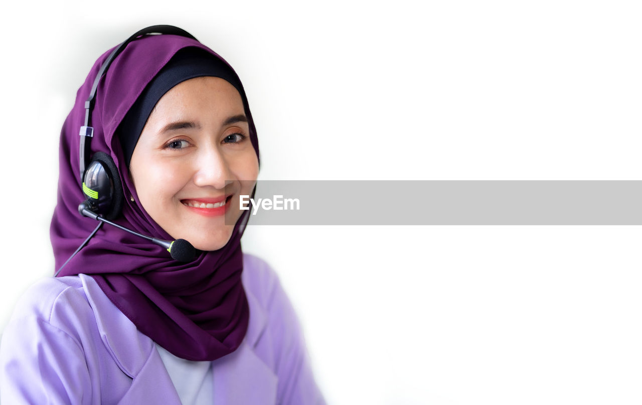 portrait of smiling young woman wearing hijab against white background