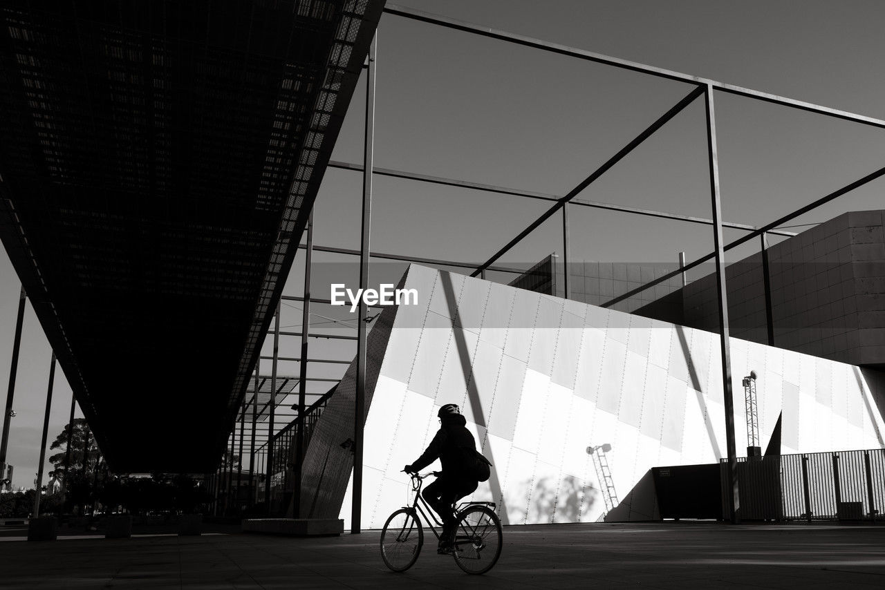 transportation, architecture, black and white, bicycle, built structure, monochrome, city, one person, black, monochrome photography, vehicle, mode of transportation, white, cycling, adult, full length, building exterior, sports, land vehicle, lifestyles, riding, city life, sky, men, travel, motion, outdoors, road, activity, wheel, silhouette, nature, day