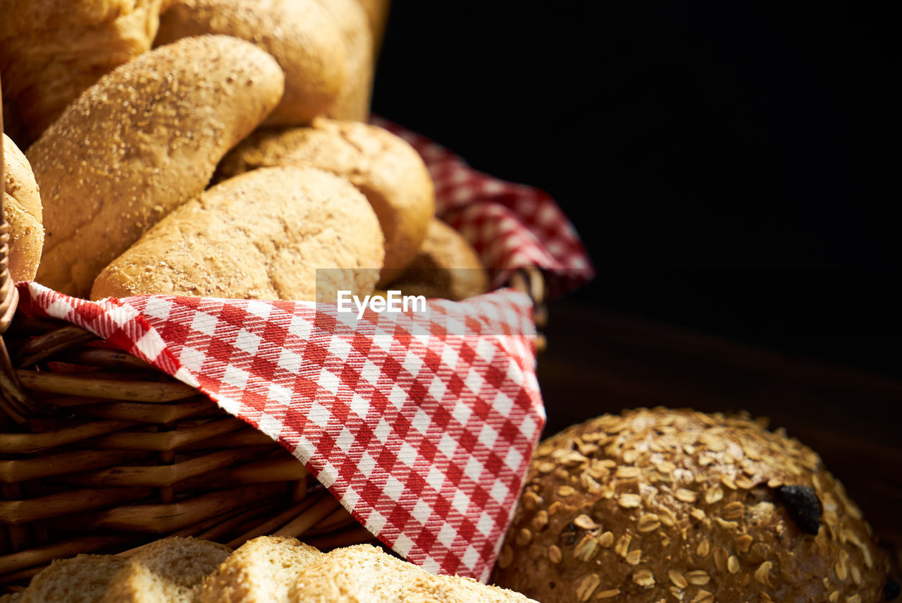 Close-up of food with wicker basket on wooden table against black background