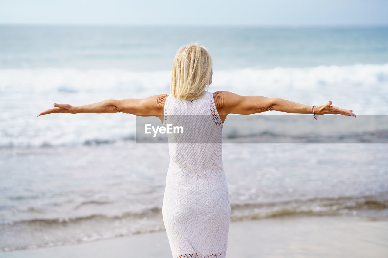 Rear view of woman standing at beach