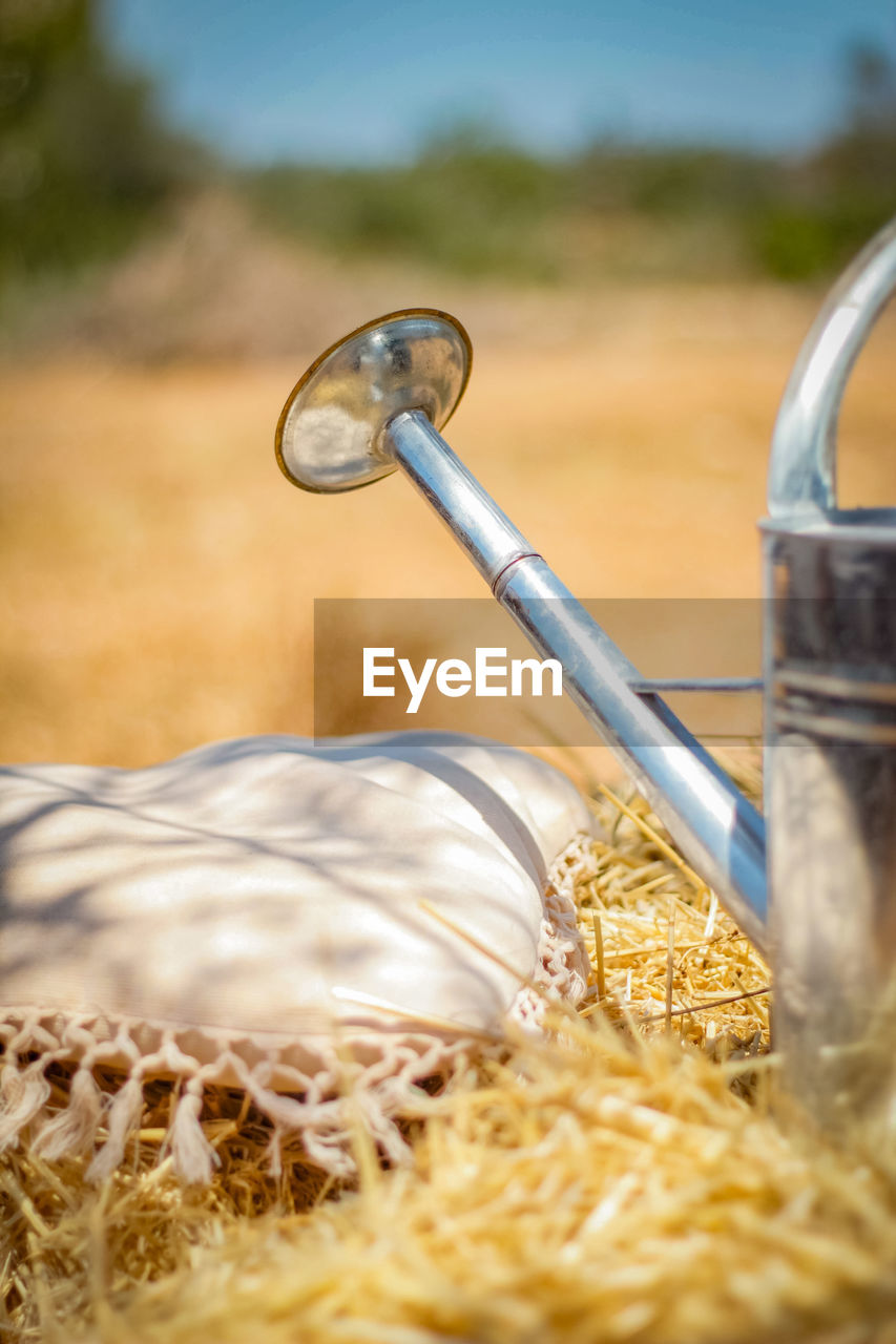 Close-up of metal water can on corn on field