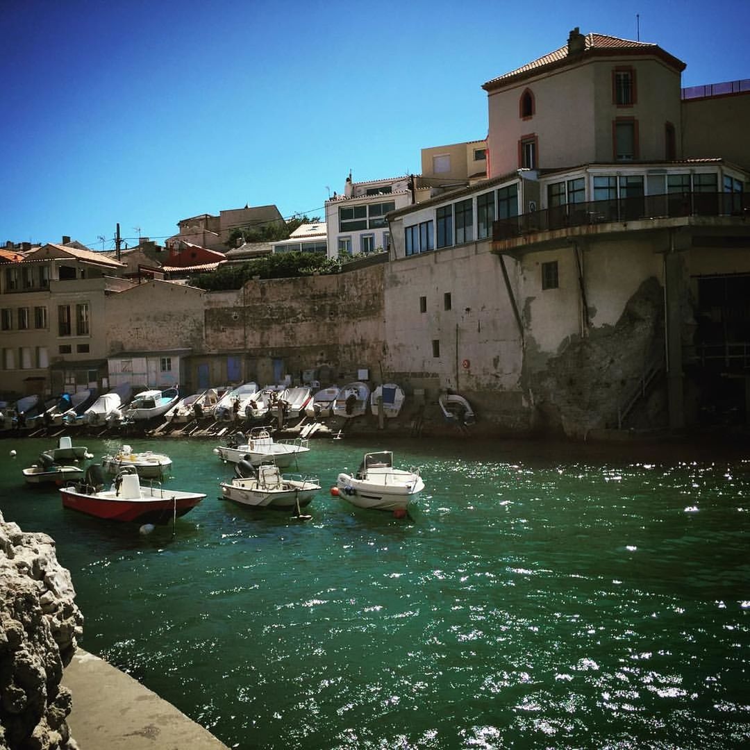BOATS IN RIVER WITH BUILDINGS IN BACKGROUND