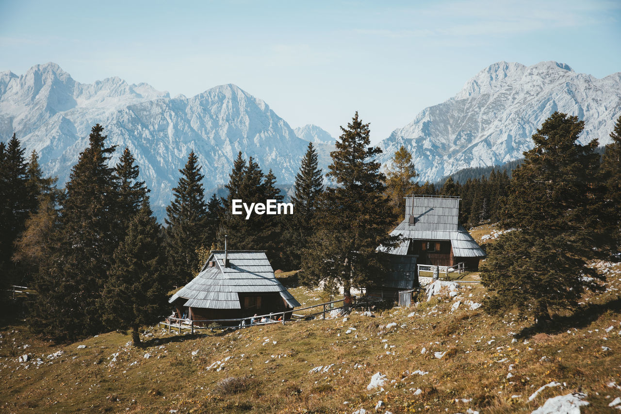 HOUSE AND TREES ON SNOW COVERED MOUNTAIN AGAINST SKY