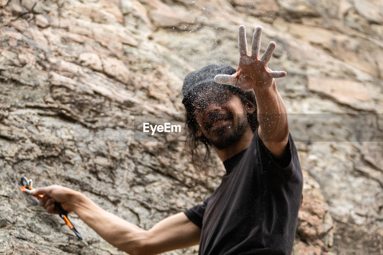 SIDE VIEW OF A MAN HOLDING ROCK IN THE GROUND