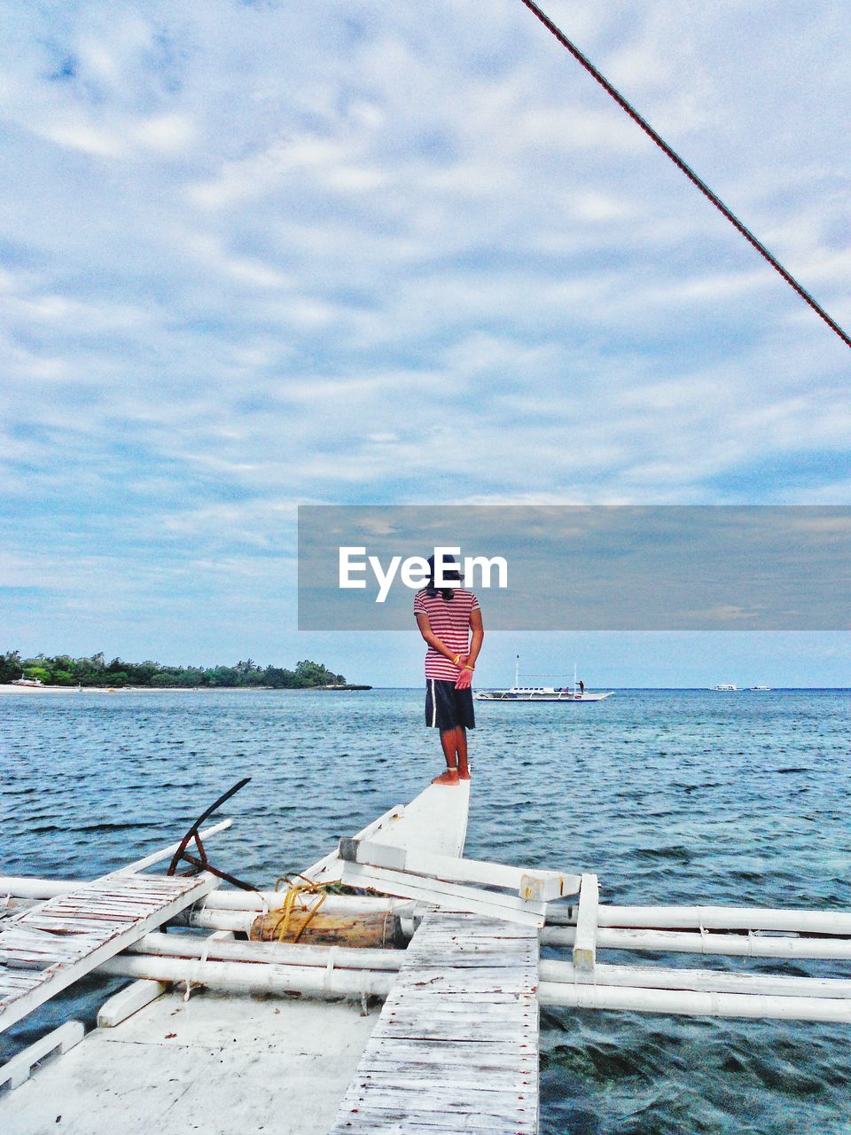 Full length rear view of man walking on pier by sea against sky