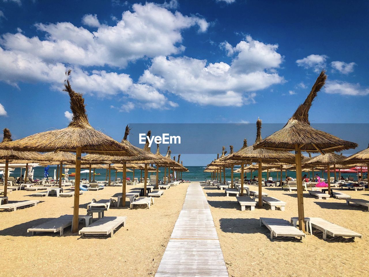 Thatched roofs umbrellas and wooden sunbeds on the beach