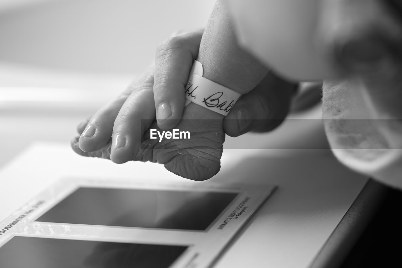 Cropped image of person holding newborn baby foot in hospital