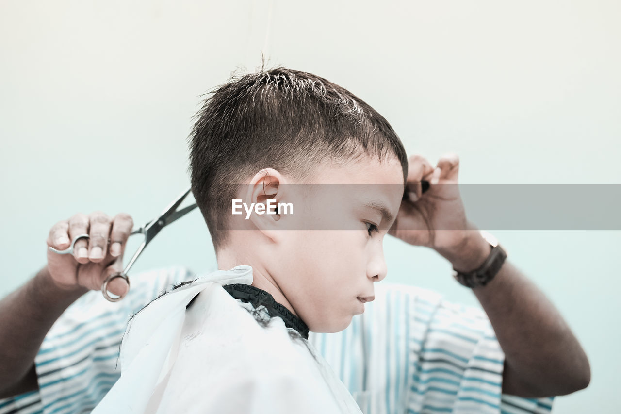 Barber cutting boy hair at salon