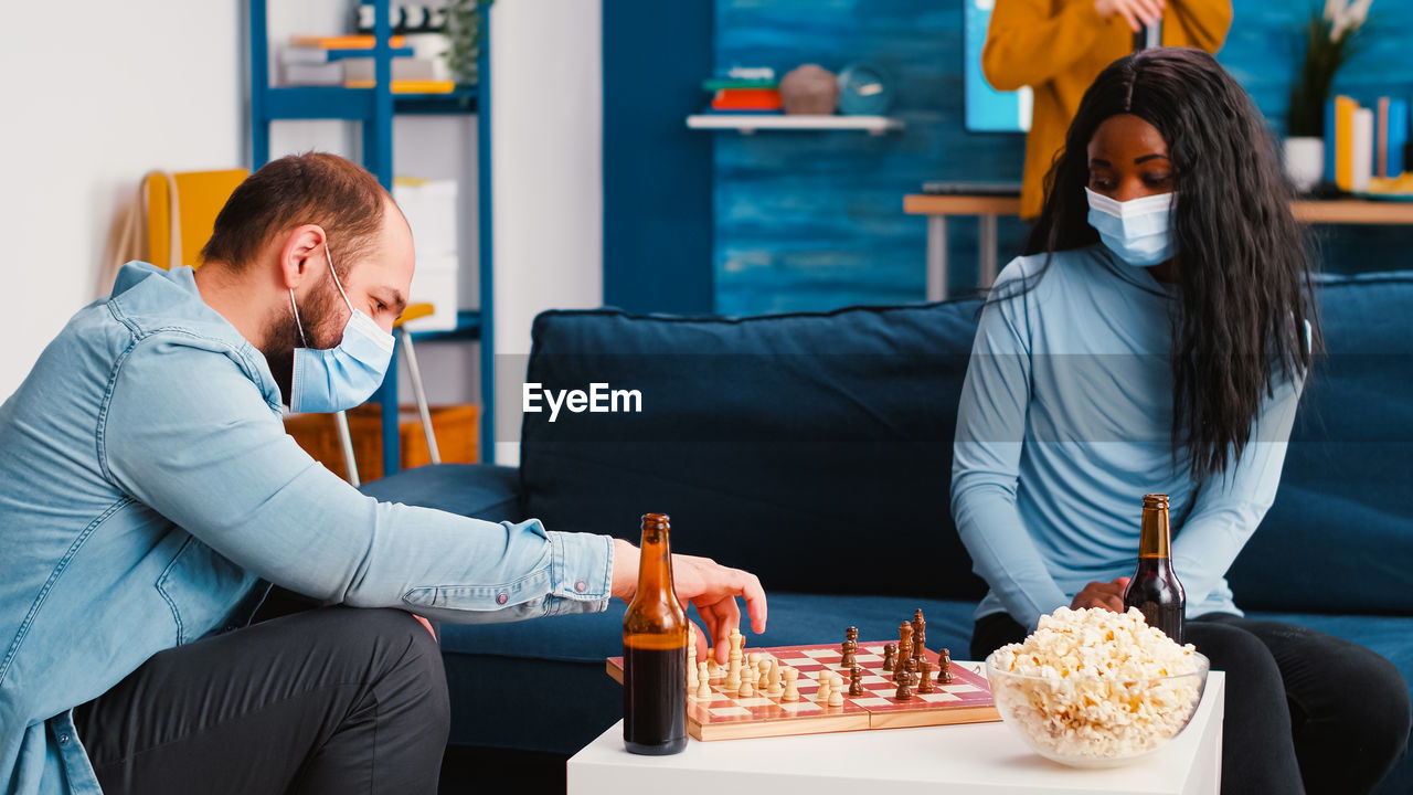 Man and woman wearing mask playing chess