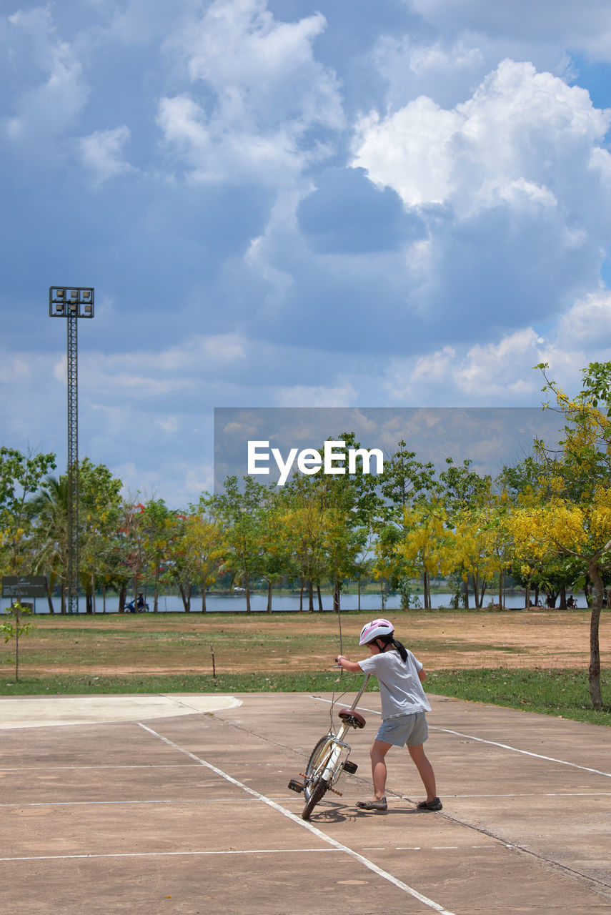 A girl try to ride the bicycle on a sunny day 