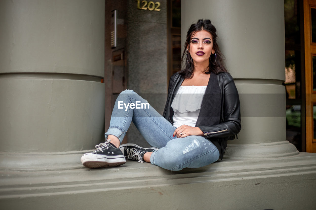 A young woman sitting on a building entrance