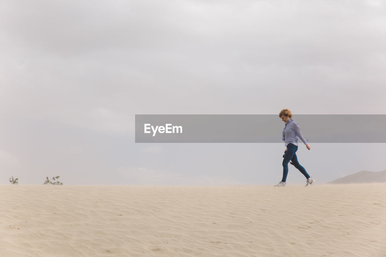 Woman walking on sand dune in desert