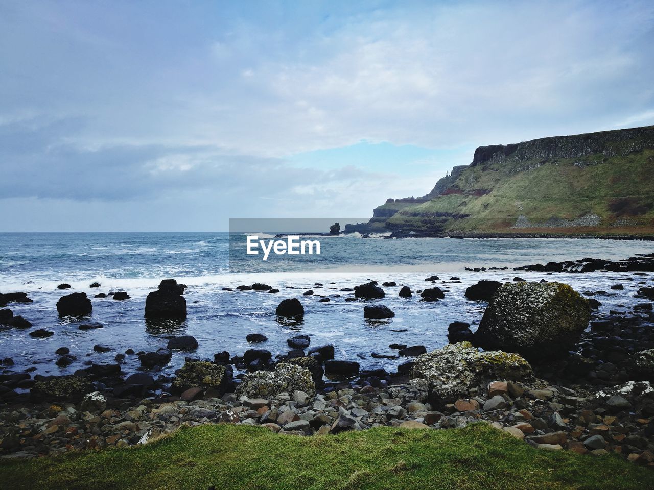 ROCKS BY SEA AGAINST SKY