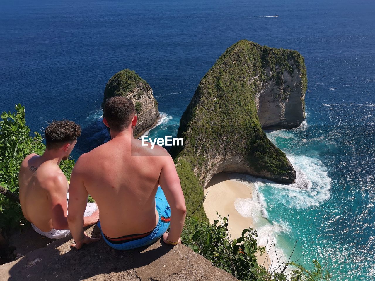 REAR VIEW OF MEN LOOKING AT SEA