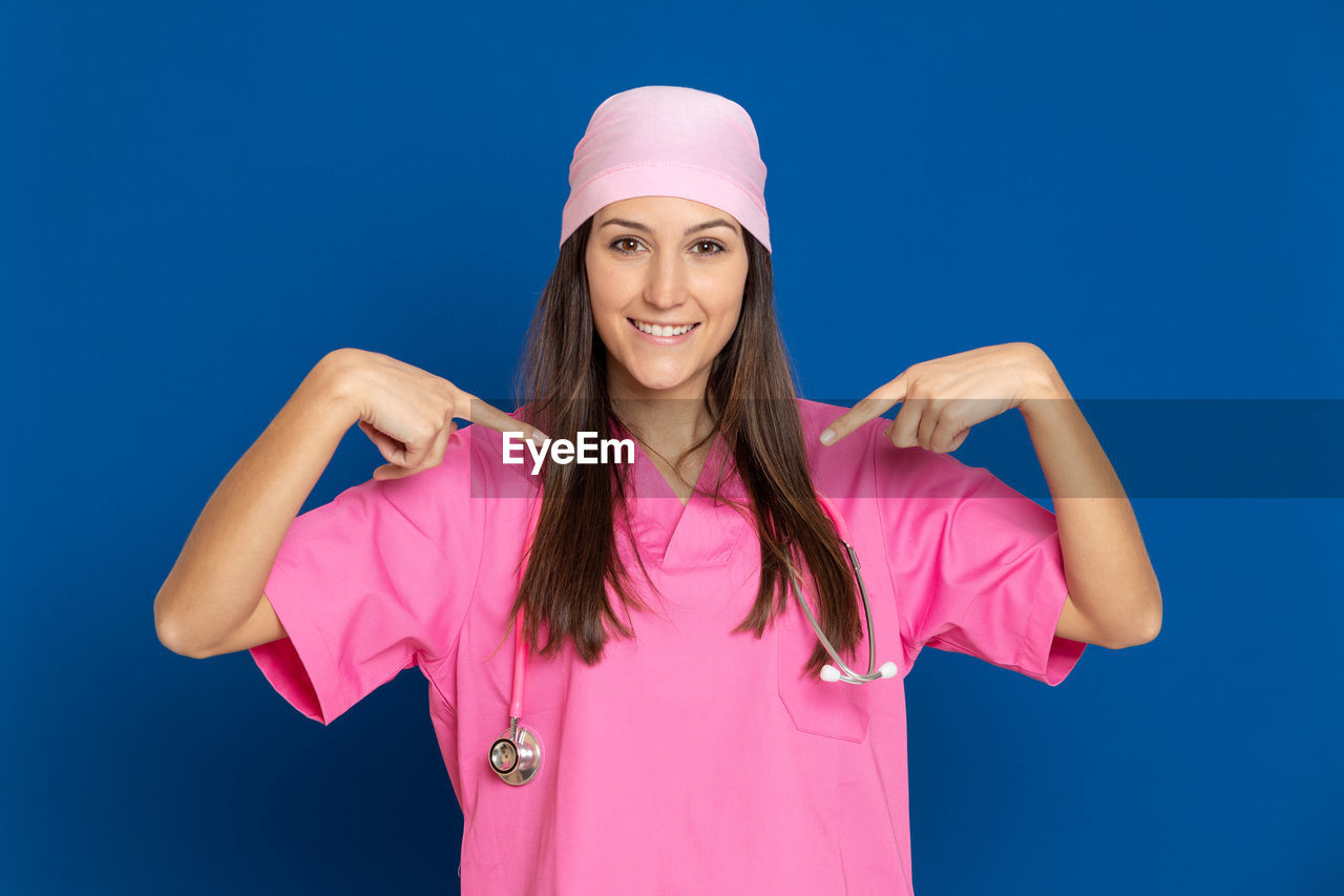 PORTRAIT OF HAPPY YOUNG WOMAN AGAINST PINK BACKGROUND