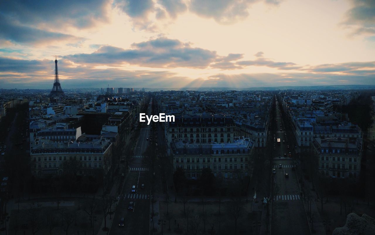 Mid distance view of eiffel tower amidst cityscape against sky during sunset