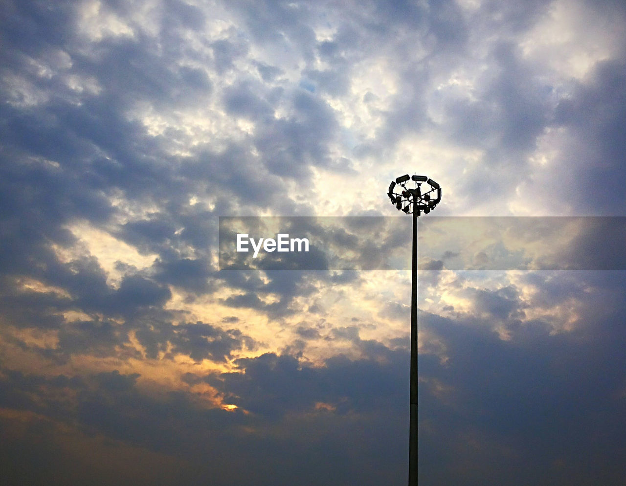 LOW ANGLE VIEW OF STREET LIGHTS AGAINST CLOUDY SKY