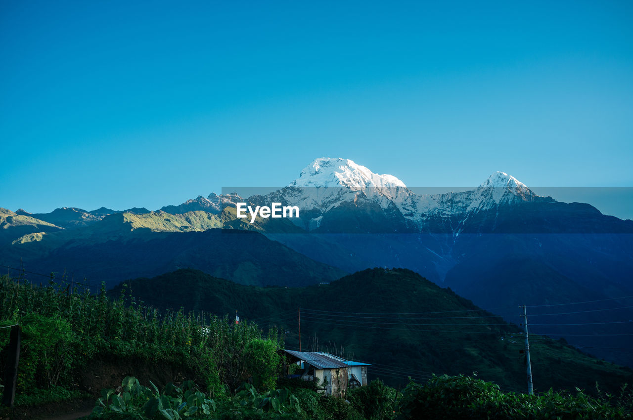 Scenic view of snowcapped mountains against clear blue sky