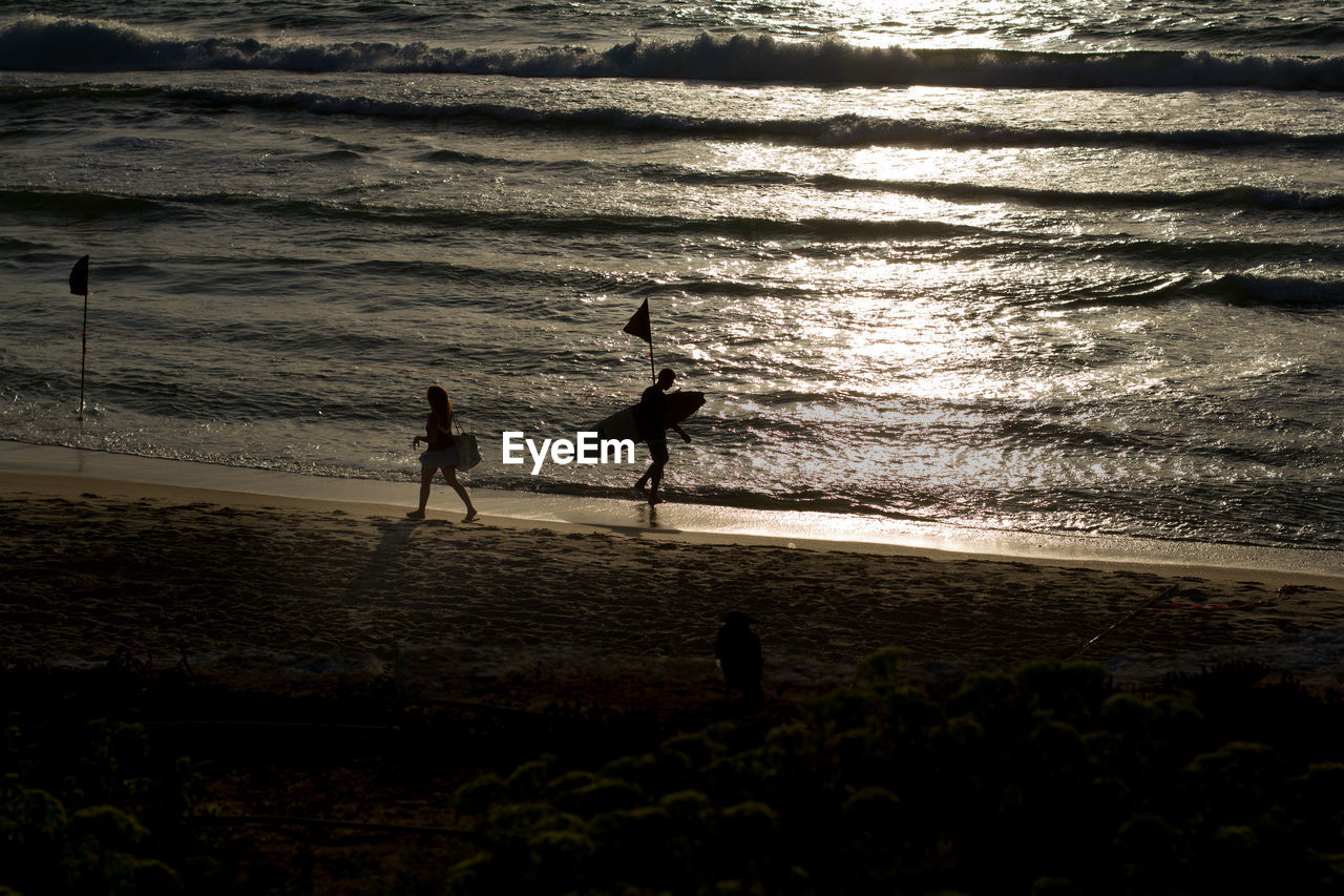 SILHOUETTE PEOPLE STANDING ON BEACH BY SEA