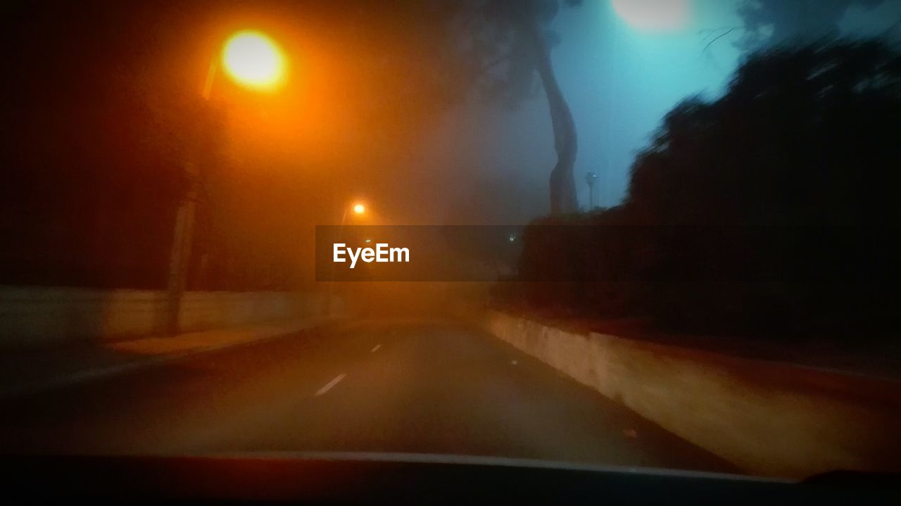 CLOSE-UP OF ILLUMINATED CAR ON ROAD AGAINST SKY