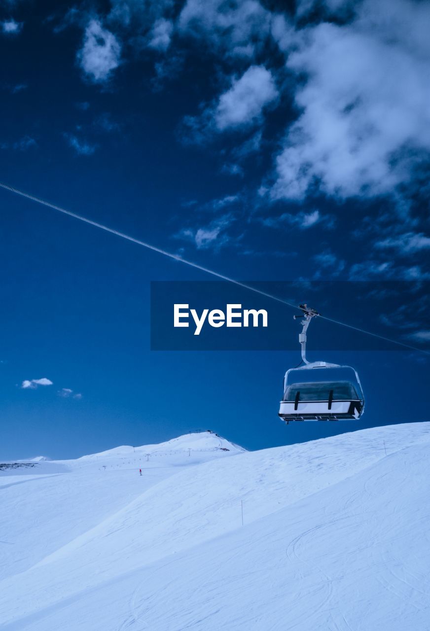 Ski lift on snowcapped mountain against sky