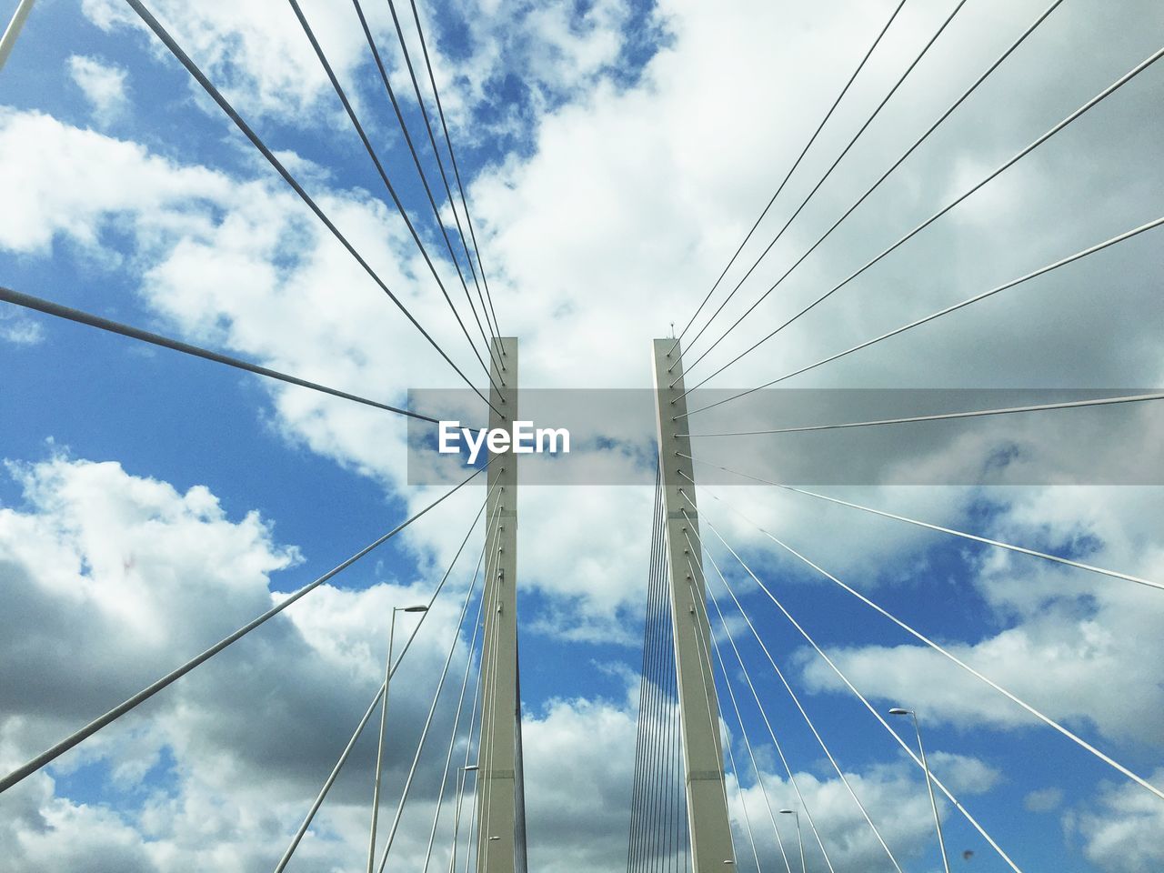 Low angle view of electricity pylon against cloudy sky