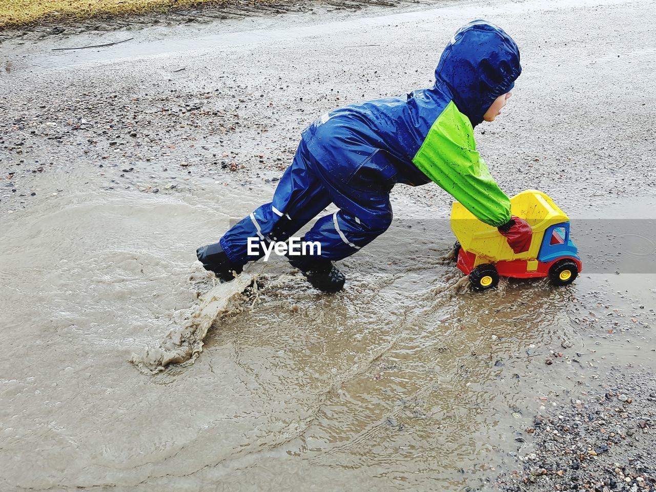 Boy playing with toy car in puddle