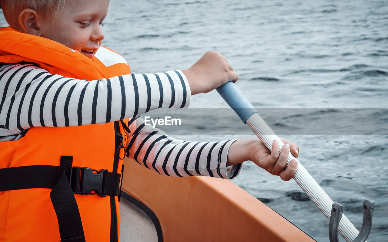 Rear view of boy on boat in sea