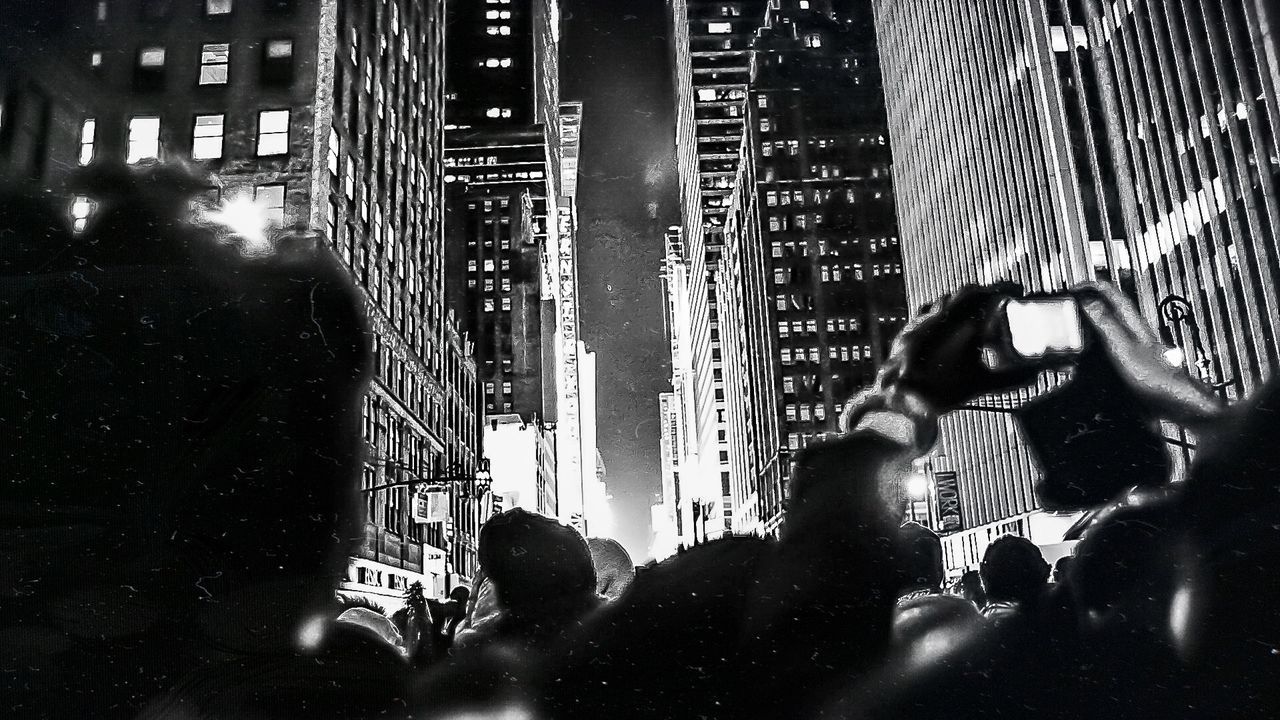PEOPLE WALKING ON ILLUMINATED CITY STREET AT NIGHT