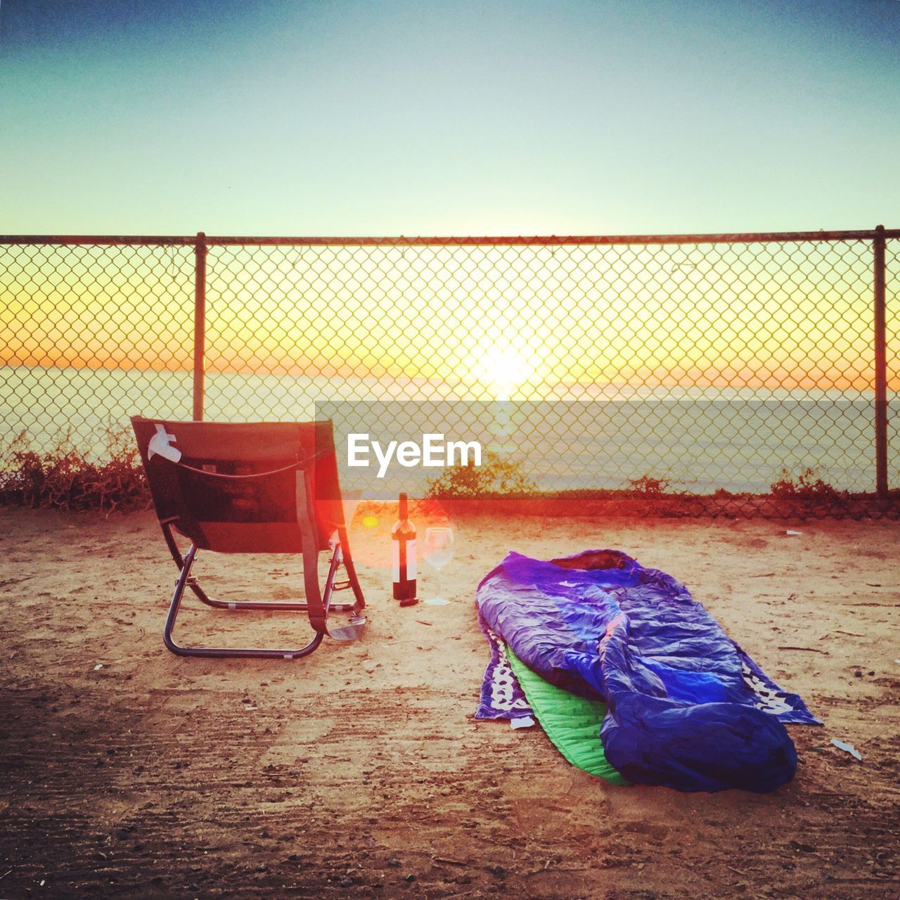 Empty chair overlooking calm sea at sunset