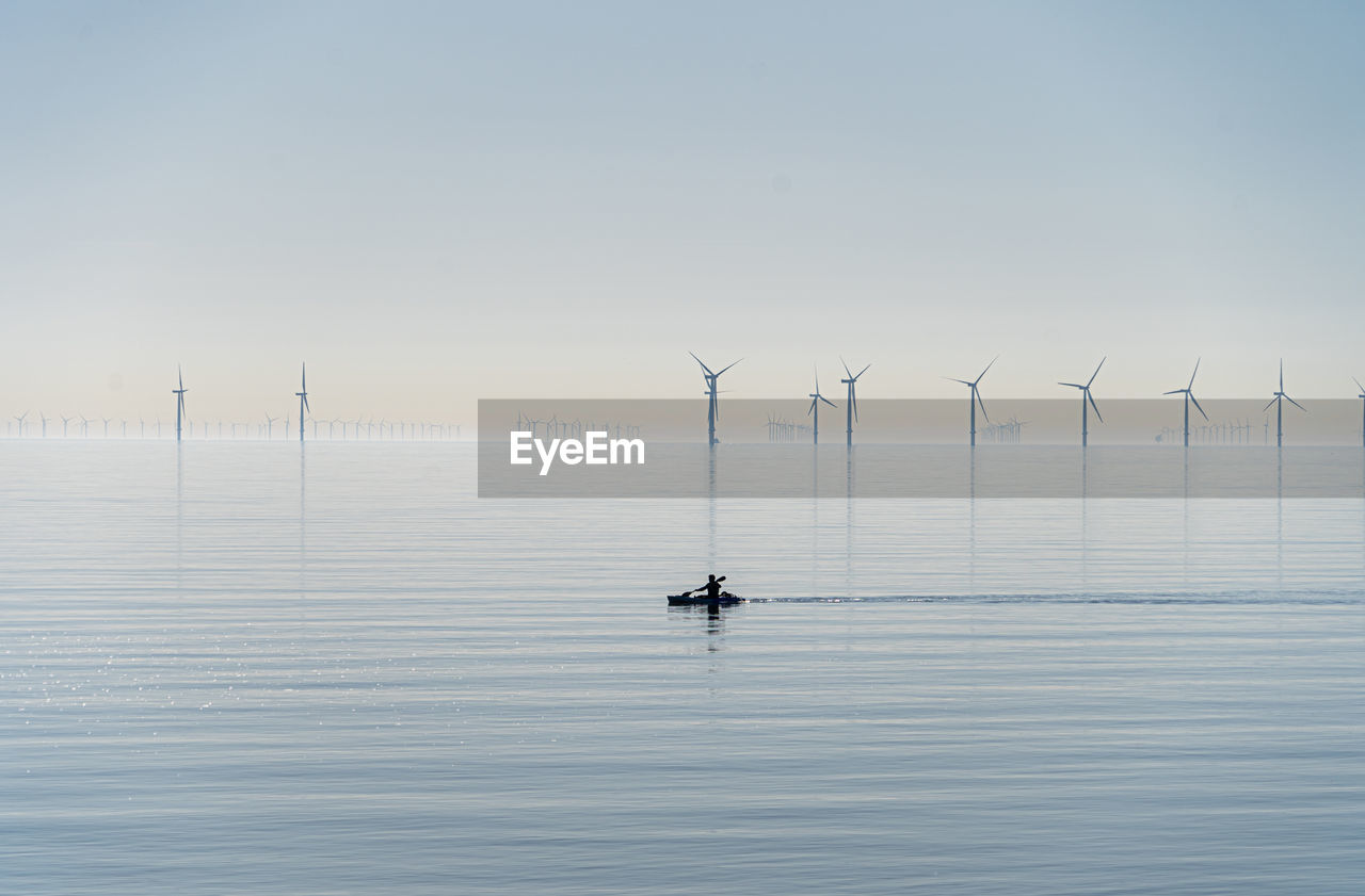 Offshore wind turbines generating renewable electricity and energy  atmospheric background image