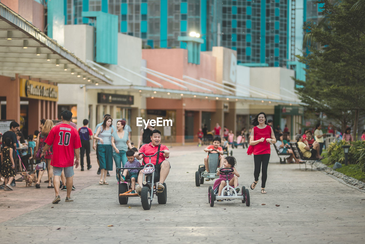 PEOPLE RIDING BICYCLES ON STREET AGAINST BUILDINGS