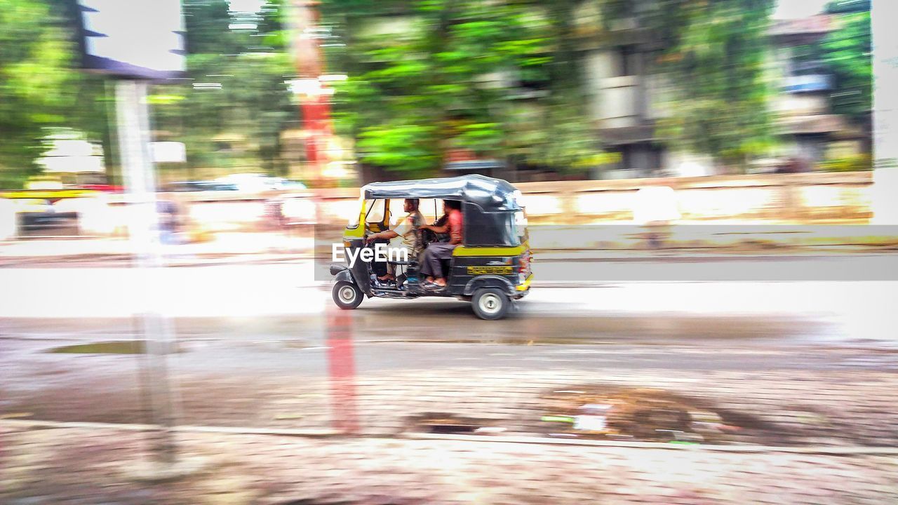 REAR VIEW OF PEOPLE RIDING BICYCLE ON ROAD