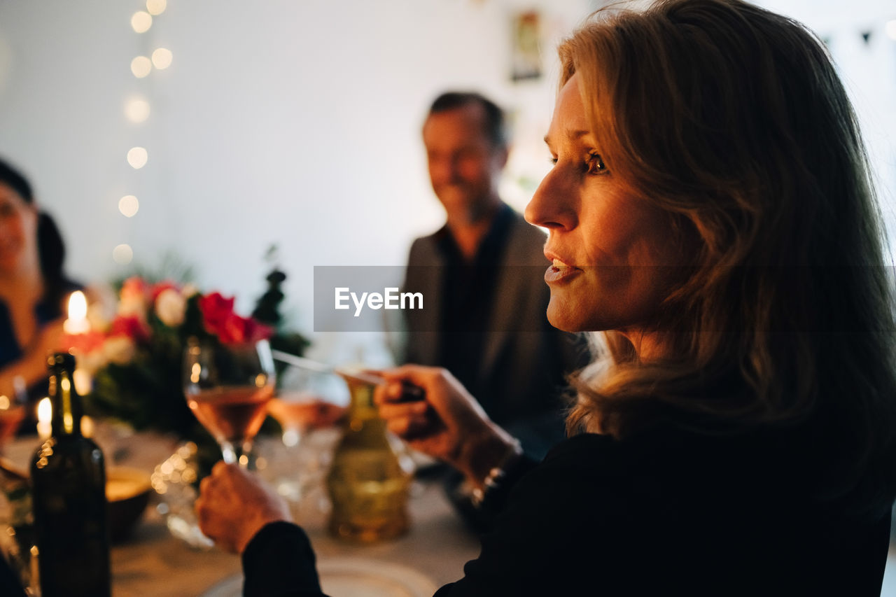 Close-up of woman raising toast with wineglass during dinner party