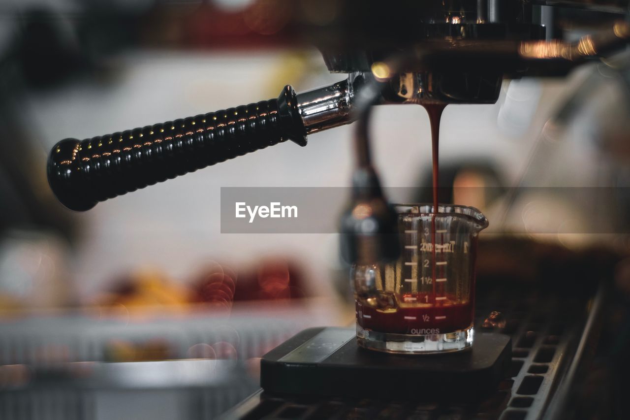 Close-up of coffee pouring in measuring cup at cafe