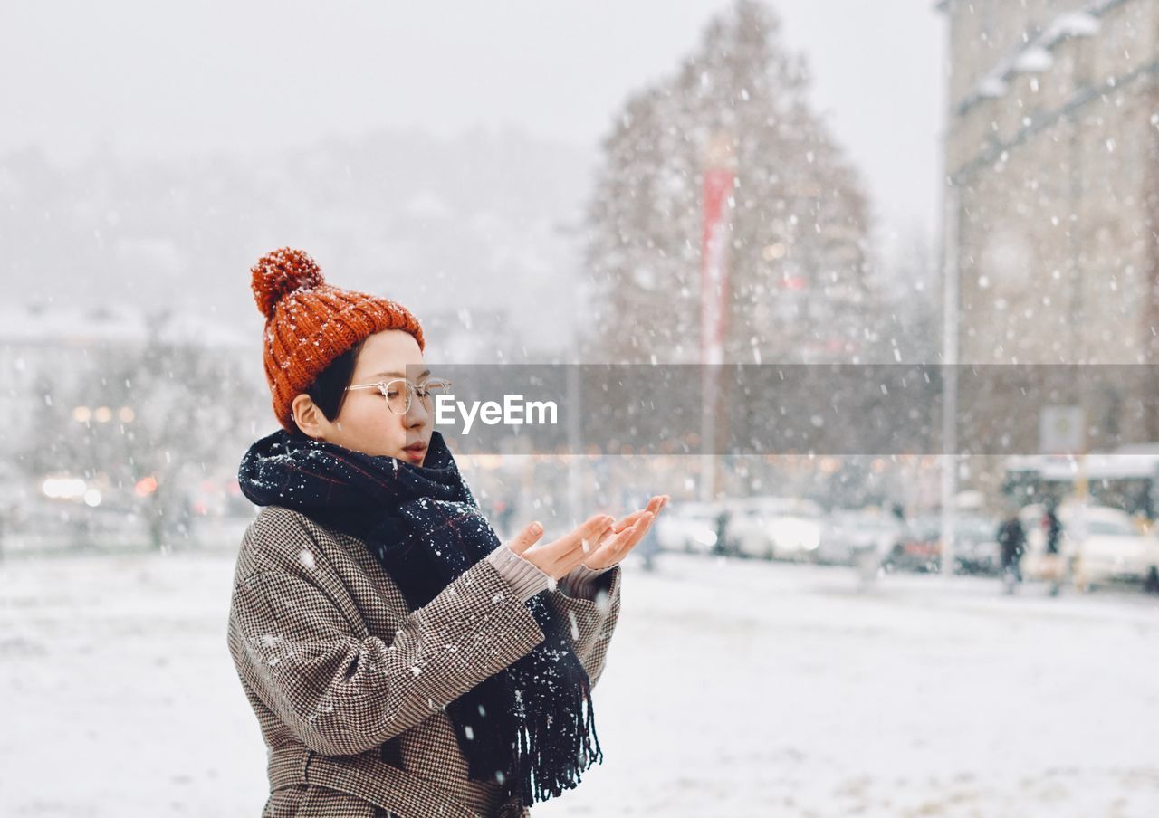 Woman standing in city during snowfall