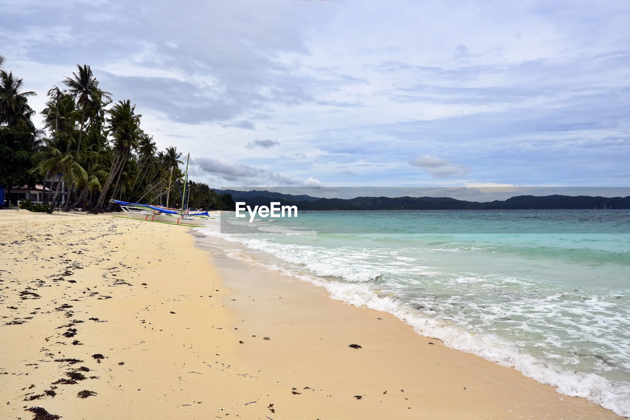 land, beach, water, sea, sand, sky, body of water, scenics - nature, nature, beauty in nature, shore, cloud, ocean, tree, travel destinations, tropical climate, tranquility, vacation, trip, holiday, travel, coast, coastline, tranquil scene, environment, water's edge, wave, palm tree, tourism, plant, wind wave, island, landscape, idyllic, sports, summer, outdoors, water sports, day, no people, motion, bay, relaxation, tropics, seascape, tropical tree, blue, coconut palm tree, non-urban scene, shoal, sun, sunlight, bay of water, horizon