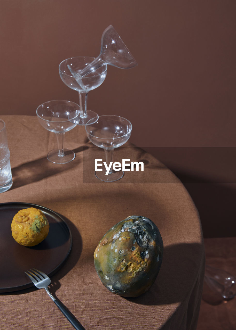 Close-up of wine glasses and rotten fruits on table