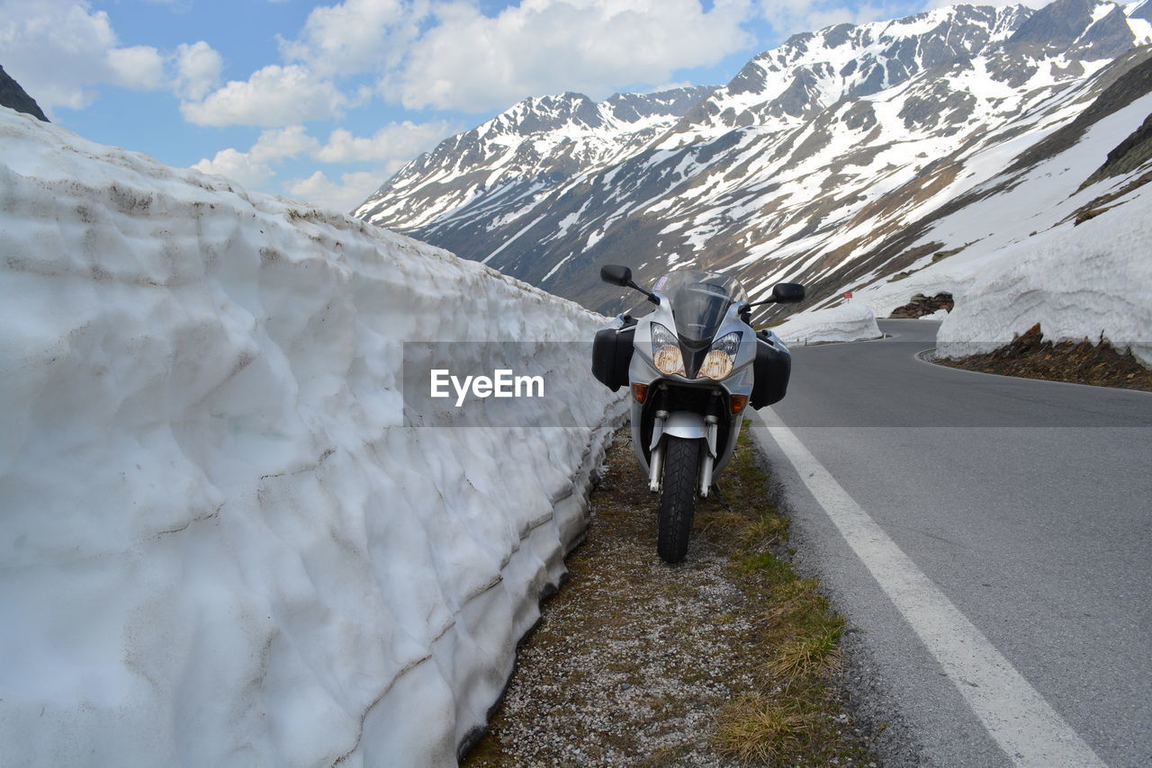 Motorcycle parked on roadside by snow retaining wall
