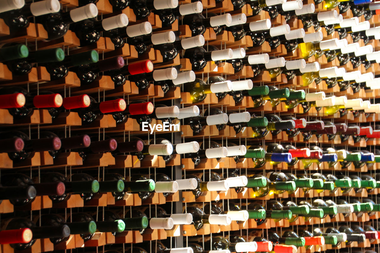 Full frame shot of multi colored wine bottles in rack