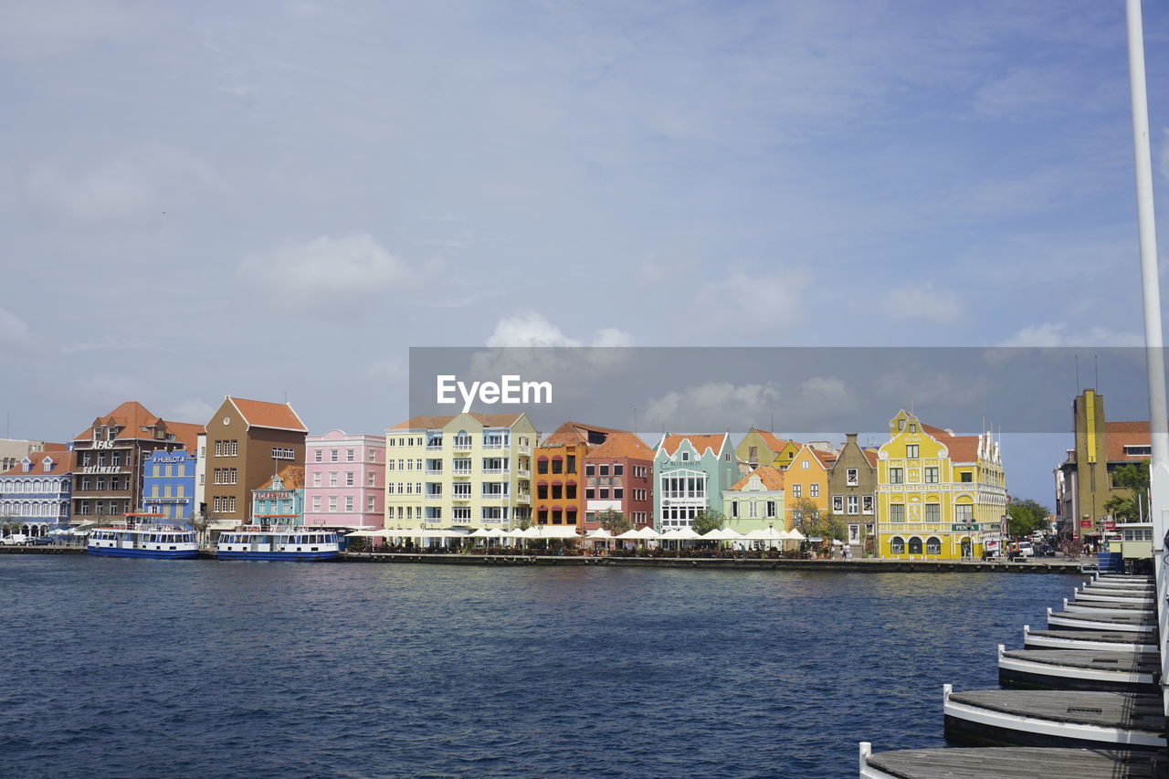 Buildings by sea against sky