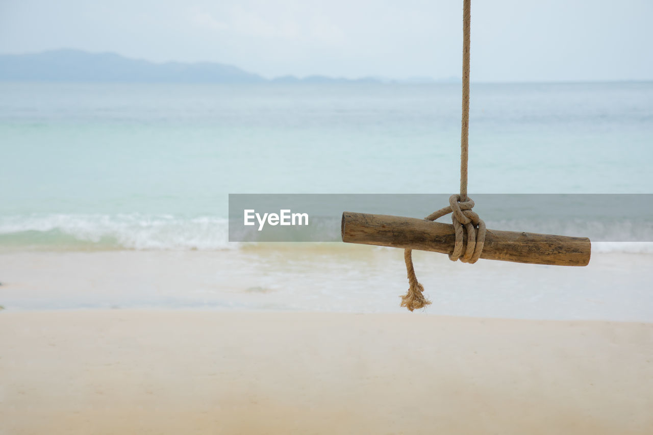Wooden logs with rope hanging on the tree at beautiful beach with gorgeous sea and mountain view 