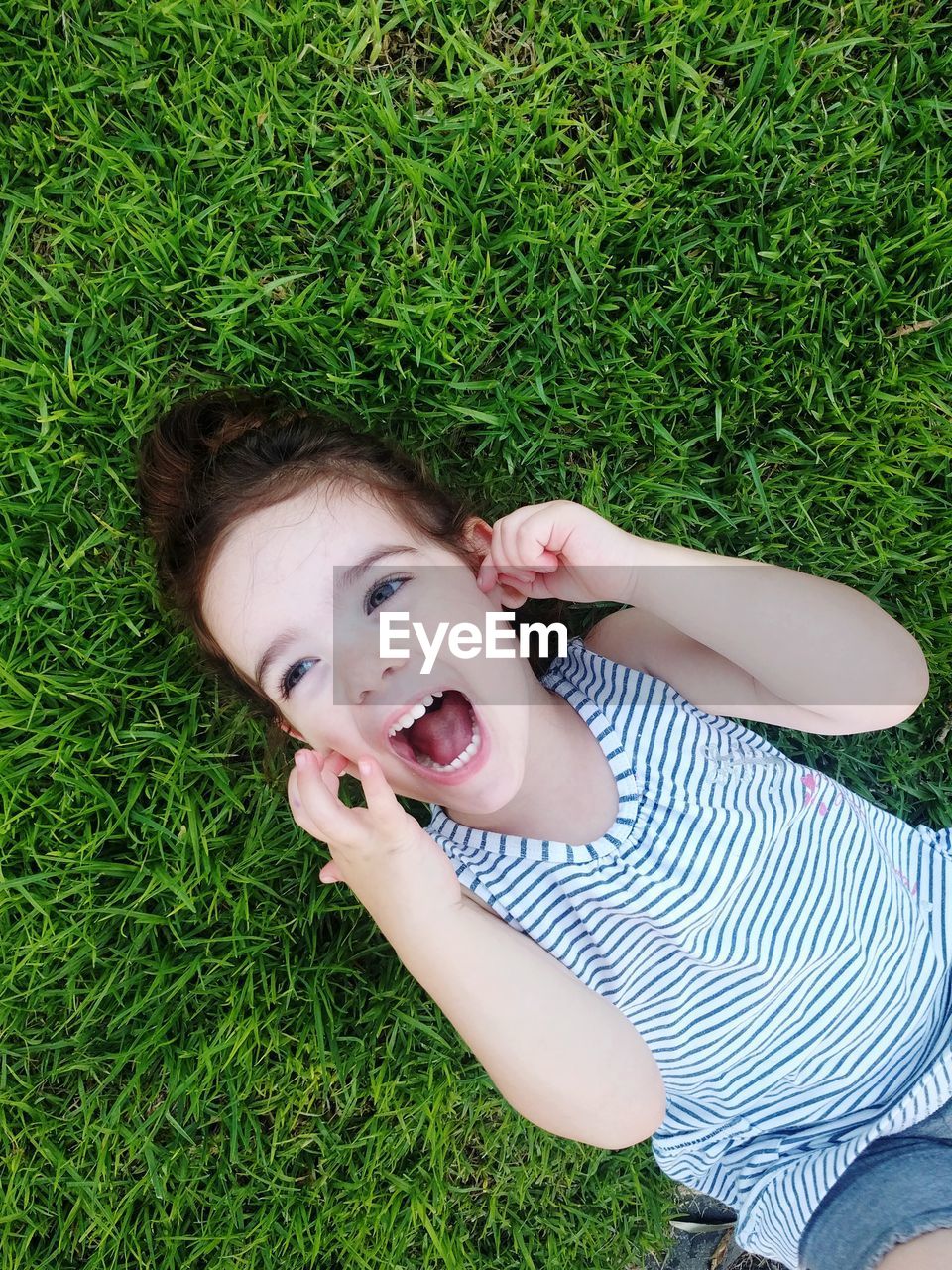 High angle view of cute girl screaming while looking away on grassy land