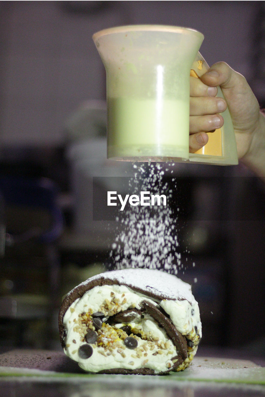 Cropped hand of woman pouring sugar on sweet food