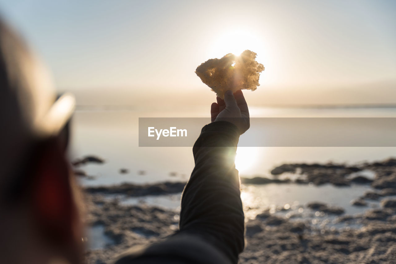 Woman on beach against sea during sunset