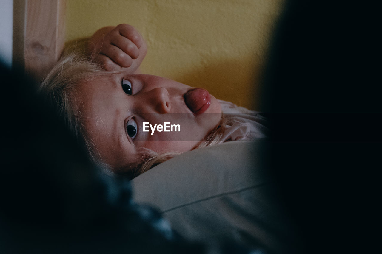 Portrait of cute girl lying down on bed at home