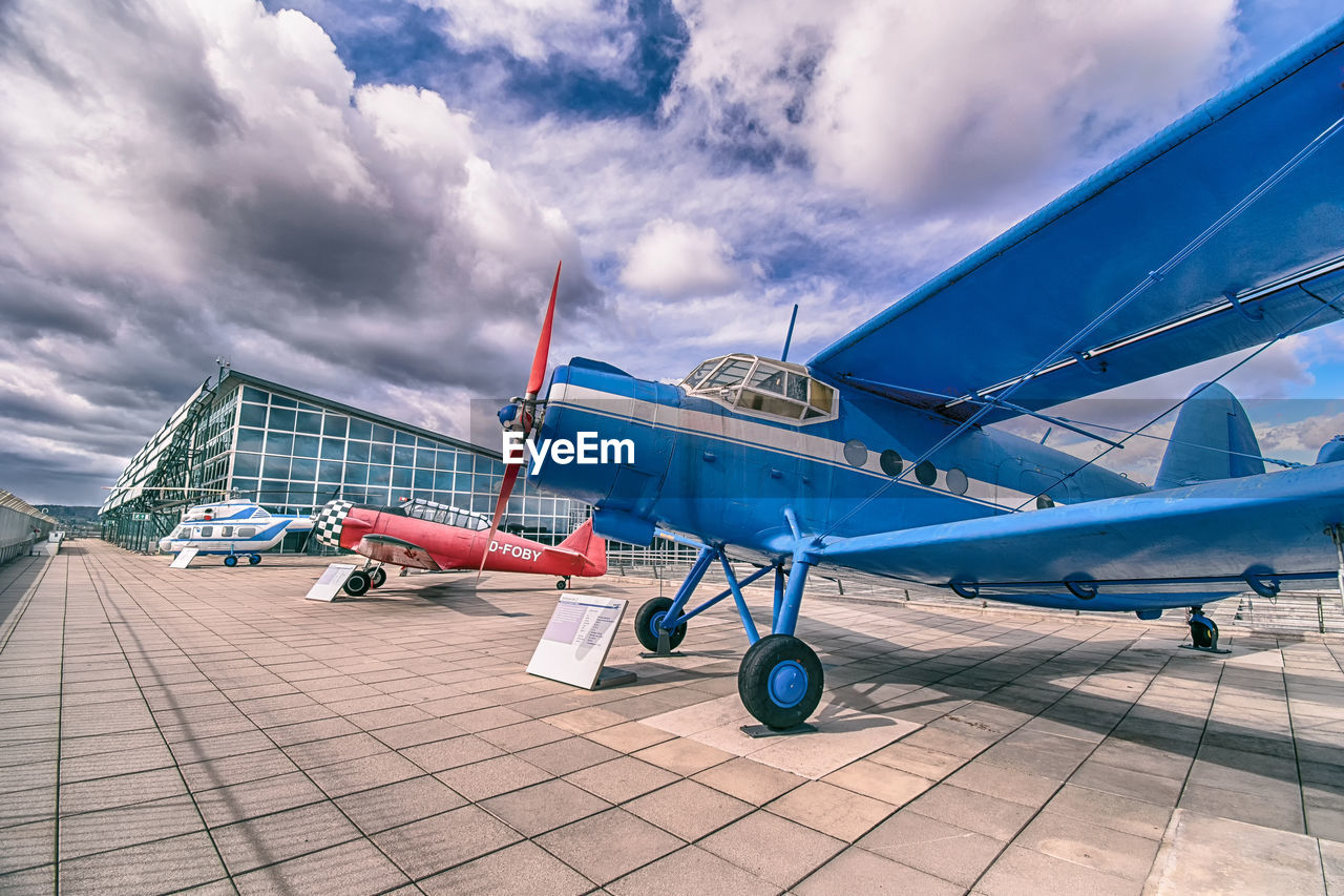 LOW ANGLE VIEW OF AIRPLANE ON AIRPORT RUNWAY AGAINST SKY