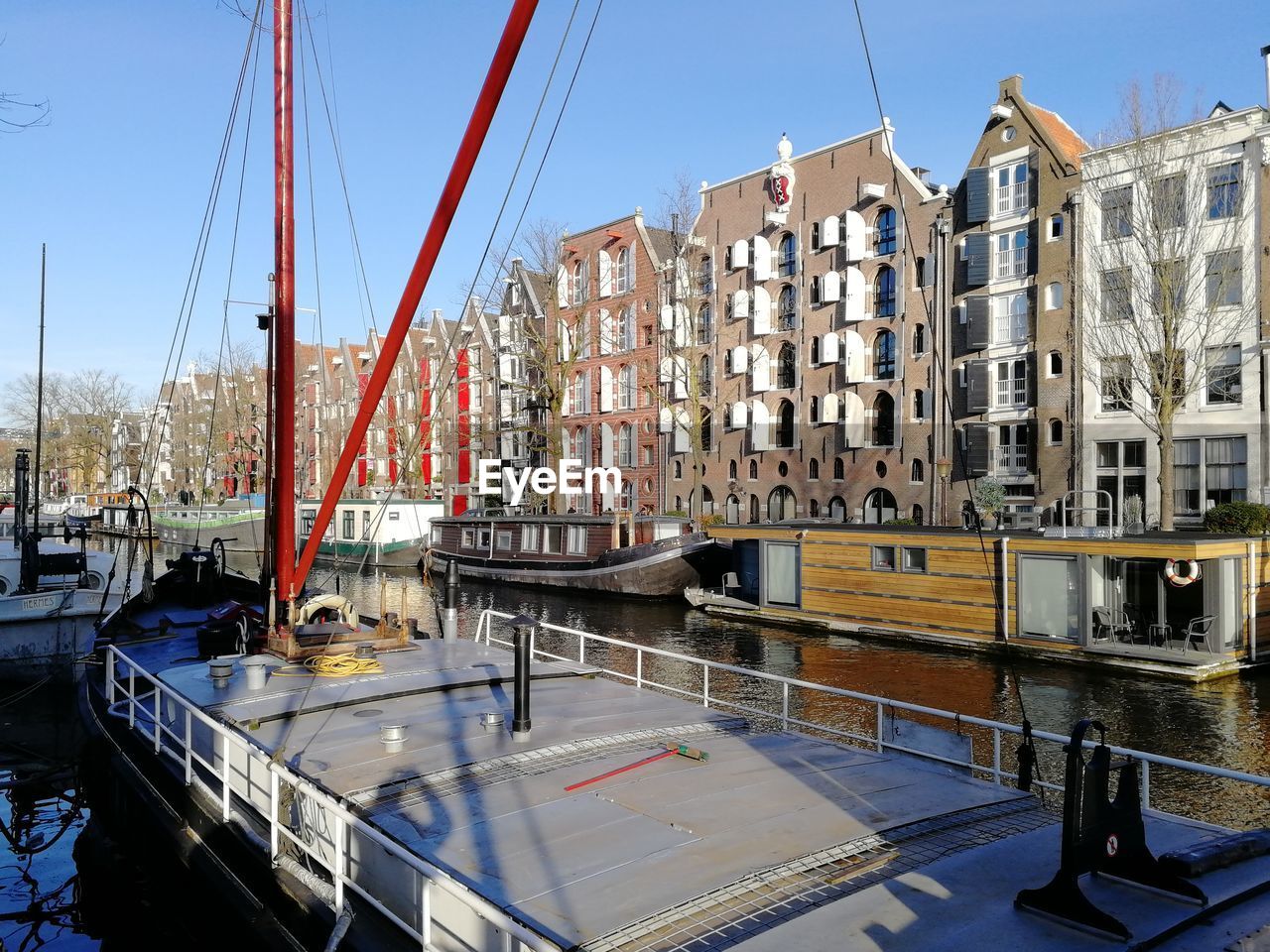 SAILBOATS MOORED ON CANAL BY BUILDINGS AGAINST SKY
